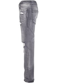 Jeans in denim grigio con una vestibilità slim, caratterizzati da dettagli vissuti e toppe sfrangiate. Design classico a cinque tasche con vita media.