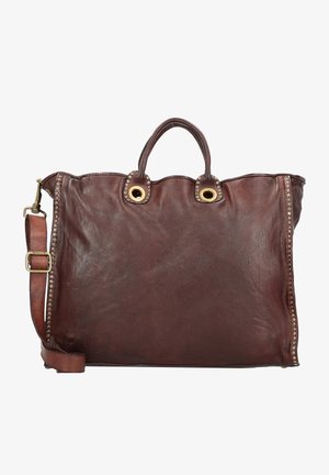 Sac fourre-tout en cuir marron avec deux poignées supérieures et une bandoulière amovible, présentant des œillets dorés et des accents cloutés sur les côtés.