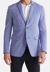 Light blue blazer made of textured fabric, featuring a single button closure, notched lapels, and front pockets. Worn over a white polo.