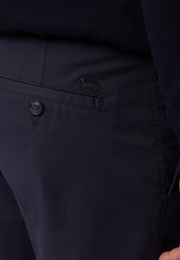 Navy blauwe chino's gemaakt van een katoenmix stof, met een knoopsluiting, subtiele logo borduursel en een gladde textuur.