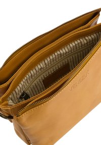 Tan læder crossover taske med to lynlåskompartments, featuring stribet stofforing og et debosseret logo. Glat tekstur og minimalistisk design.