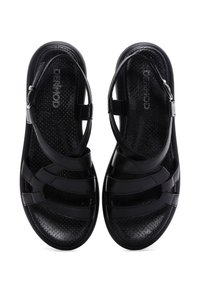 Black sandals featuring a strappy design with thin straps, a textured footbed, and an adjustable ankle buckle for secure fit.