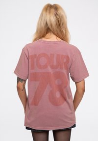 Unisex oversized cotton t-shirt in dusty rose with "TOUR 78" printed in large, faded red letters on the back. Short sleeves, crew neckline.