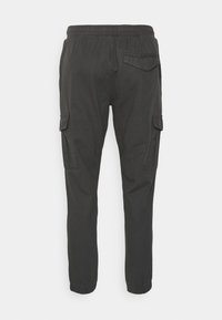 Cargo kalhoty v tmavě šedé barvě, s elastickým pasem, zúženými nohavicemi, bočními cargo kapsami a nášivkou na zadní kapse.