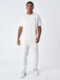 Witte katoenen t-shirt met een ronde halslijn en bedrukte logo, gecombineerd met bijpassende witte katoenen joggers met cuffs bij de enkels.