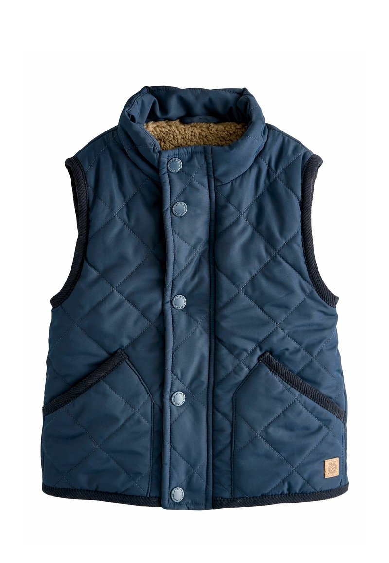 Navy quilted vest featuring a high collar, front snap buttons, and two side pockets. Interior lined with tan faux fur. Trimmed with dark edging.