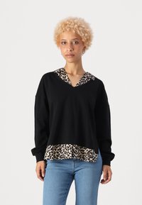 Musthave muströök, millel on leopardimustriga kaelus ja ääred. Omab pikki varrukaid ja lõdvestunud istuvust. Kangas näeb välja pehme ja tekstuurne.