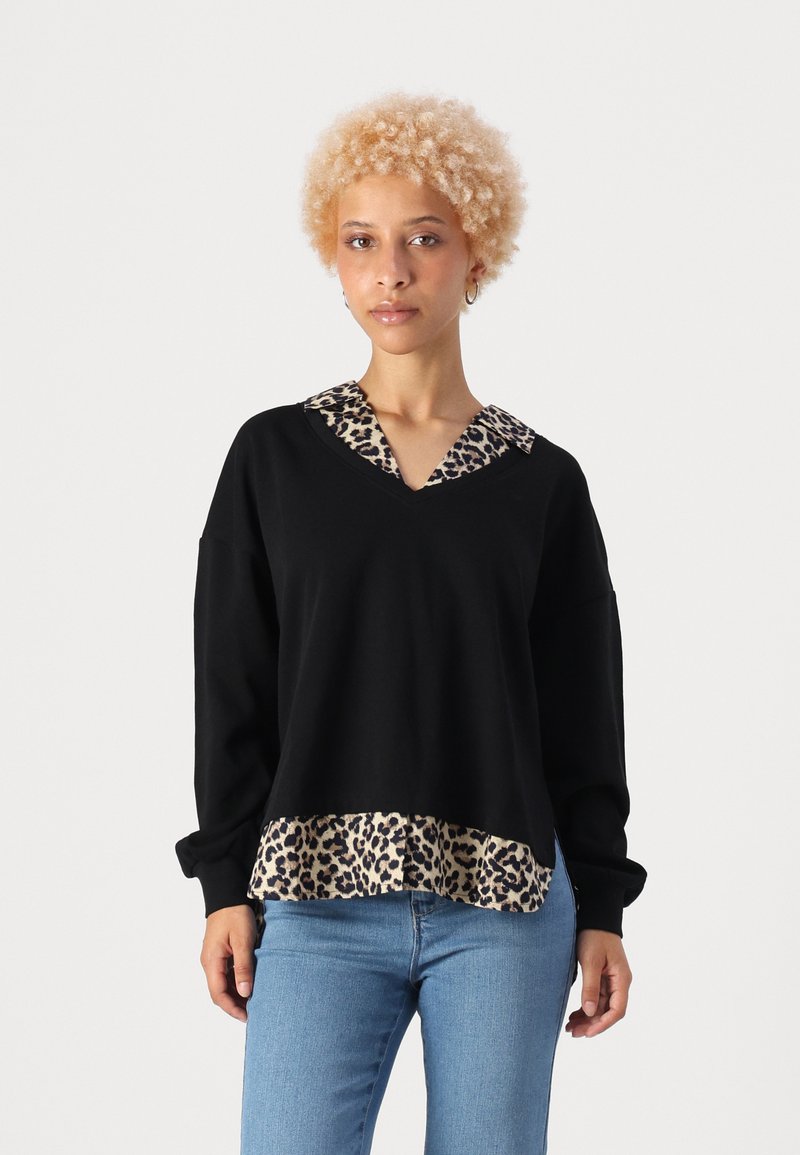 Musthave muströök, millel on leopardimustriga kaelus ja ääred. Omab pikki varrukaid ja lõdvestunud istuvust. Kangas näeb välja pehme ja tekstuurne.