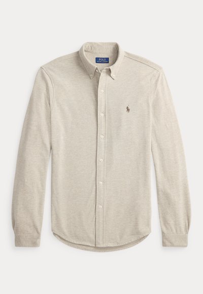 Camisa cinza claro de manga comprida com botões, feita de tecido macio. Apresenta um colarinho clássico, bainha curva e um pequeno logótipo no peito.