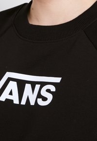 Felpa nera con collo a coste e un prominente logo bianco "VANS". Tessuto morbido con maniche raglan.