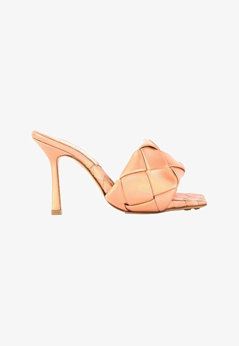 Mule beige à talon haut avec bride en cuir tressé rembourrée et bout carré sur fond blanc.