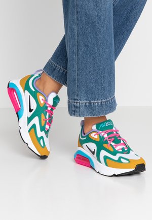 Stopy w kolorowych sneakersach Nike Air Max 200 z różowymi sznurówkami oraz niebieskimi, zielonymi i żółtymi akcentami, w połączeniu z niebieskimi dżinsami.