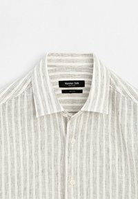 Vit linneskjorta med tunna vertikala svarta ränder, knäppt framtill och med en spridd krage, märkt Massimo Dutti.