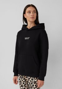 Zwarte hoodie van een katoenmix, met een voorkcontour en geborduurde tekst. Gestyled met lichtgekleurde, gestreepte bottoms.