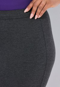 Tummanharmaa istuva hame, joka on valmistettu pehmeästä ja joustavasta kankaasta. Hameessa on sileä vyötärö ja hienovarainen tekstuuri. Ei näkyviä kuvioita tai yksityiskohtia.