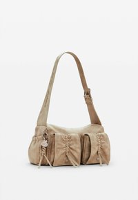 Beige suede shoulder bag with gathered front details, single strap, and small leather charm attached to a side loop. Smooth texture.