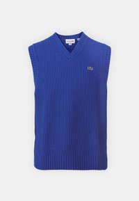 Mouwloos blauw gebreid vest met een V-hals. Heeft een geribbelde textuur en een klein groen Lacoste-logo op de borst.