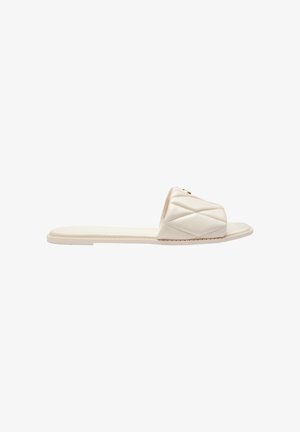 Flat beige slide sandal with cushioned, quilted single wide strap and open toe, shown from side on white background.