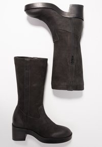 Czarne skórzane botki za kostkę o gładkiej fakturze, z zamkiem błyskawicznym z boku i masywnym obcasem. Posiadają okrągły czubek i minimalistyczne detale przeszycia.