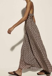 Maxi-kjole i brunt med et gentaget hvidt bølgemønster, med lav ryg og udskårne sider, lavet af letvægtsstof.
