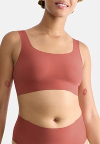 Rustfarget bralette med firkantet halslinje, laget av glatt materiale. Har brede stropper og en minimalistisk design.