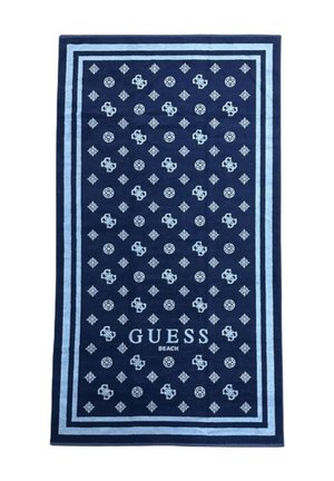 Blå strandhåndklæde med diamantmønster og logo, med lysblå kanter og teksten "GUESS BEACH" nederst. Fremstillet af blødt stof.