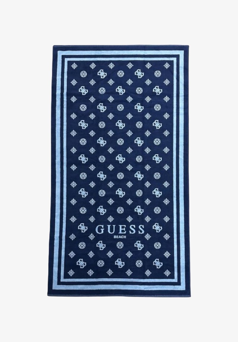 Asciugamano da spiaggia blu con motivo a diamante e logo, con bordature azzurre e la scritta "GUESS BEACH" in basso. Realizzato in tessuto morbido.