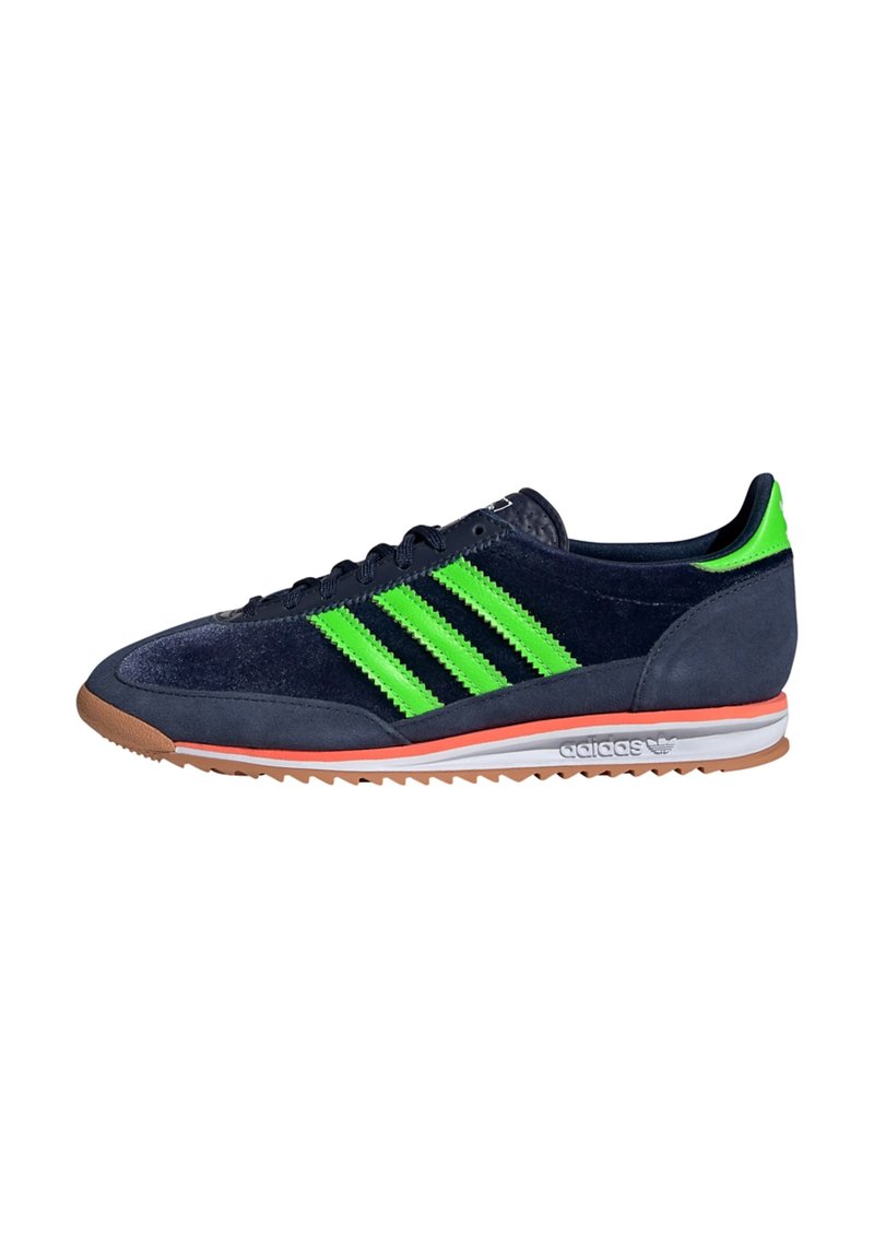Pantofii sport din suede bleu cu trei dungi verzi îndrăznețe, talpă portocalie și intermediar alb. Caracterizată printr-un profil jos și o suprafață texturată.