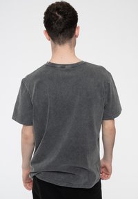 Gray short-sleeve t-shirt with a soft, faded texture and slight distressing along the neckline and hem, featuring a relaxed fit.