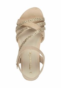 Sandalo beige con cinturini, realizzato in morbida pelle scamosciata, dettagli a piramide dorata sui cinturini e un design minimalista. Tacco piatto e punta aperta.