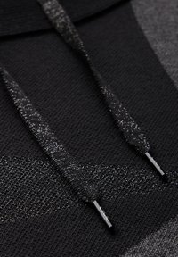 Felpa nera a maglia con un motivo testurizzato, dotata di lacci glitterati neri e punte metalliche. Superficie liscia e lucentezza sottile.