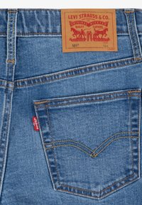 Blå denimjeans med en läderlapp märkt "Levi Strauss & Co." och karakteristisk sömnad på bakfickorna.