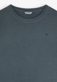 T-shirt à col rond gris foncé avec un petit logo brodé de skull et crossbones sur la poitrine gauche et étiquette de la marque Scalpers à l'intérieur du col.
