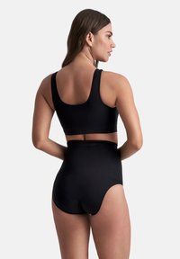 Zwarte high-waisted bikini onderkant in combinatie met een bijpassende sportbeha, met een gladde stof en een strakke pasvorm, gezien vanaf de achterkant.