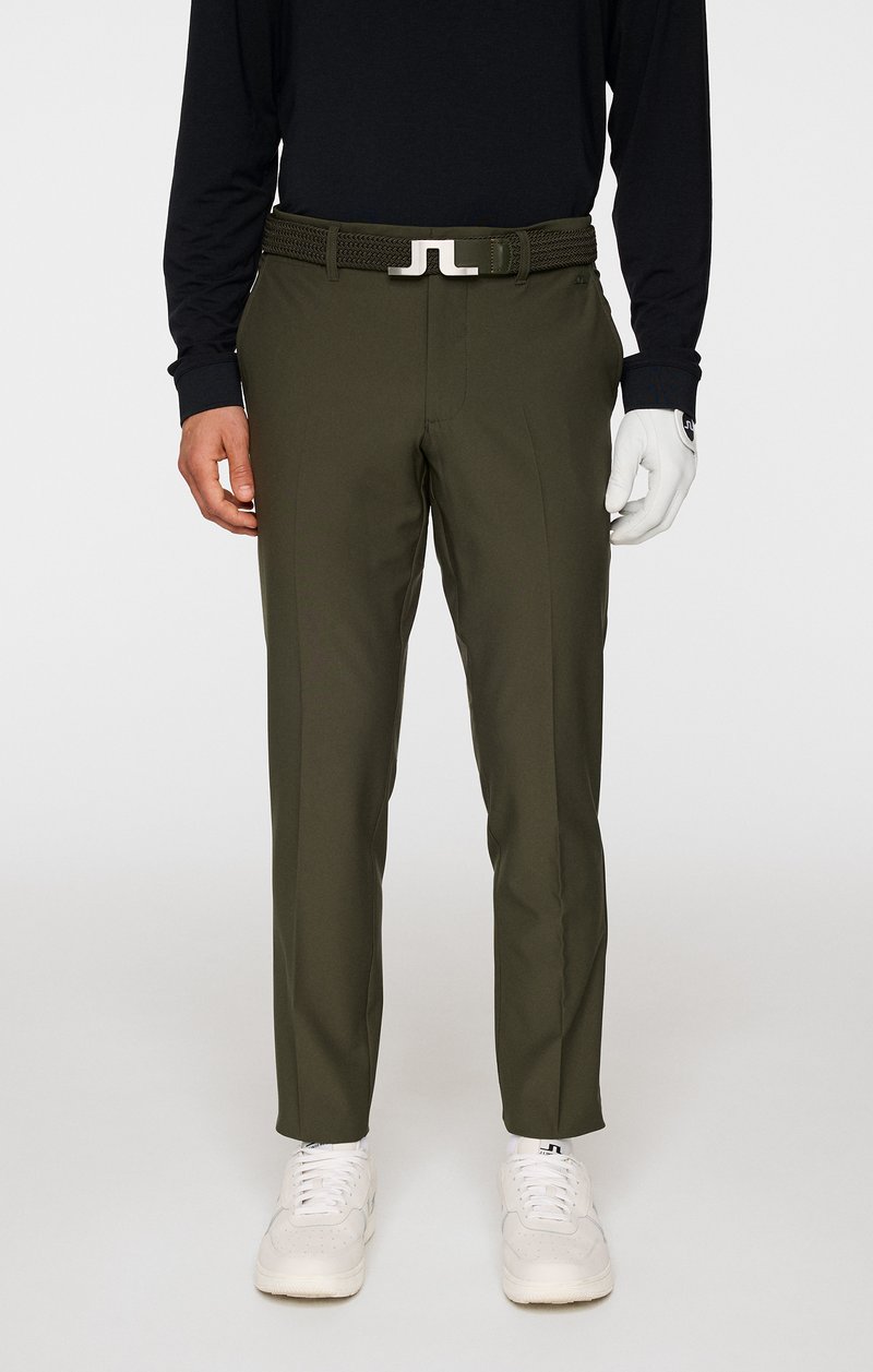 Oliwkowe spodnie golfowe o wąskim kroju, z przodu z zaszewkami i plecionym paskiem. Noszone z czarną bluzą z długim rękawem i białymi trampkami.