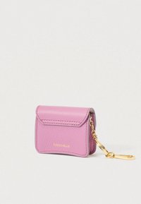 Small pink textured leather wallet with gold chain and clasp, embossed brand name COCCINELLE on front flap.