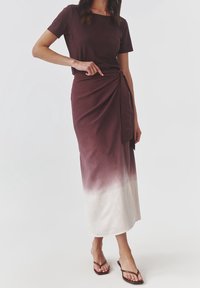 Bruine top met korte mouwen gecombineerd met een lange wikkelrok met een ombré-effect, die verloopt van donkerbruin naar wit.