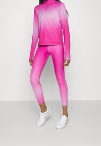 Completo atletico rosa con gradiente di colore da chiaro a scuro. Maglia a maniche lunghe con colletto a mezza zip e leggings aderenti. Realizzato in materiale morbido.
