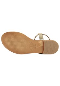Sandal in beige chiaro con suola in gomma testurizzata, cinturini intrecciati e tacco piatto. Presenta il logo del marchio e i dettagli delle taglie impressi sulla suola.