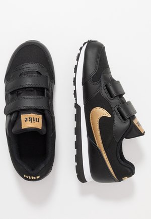 Sorte Nike-sneakers med velcrolukninger, en guld accent swoosh, glat syntetisk materiale og en tekstureret gummisål.