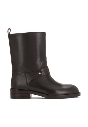 Bottine noire en cuir mi-mollet avec un petit talon empilé, bout rond, languette à l'arrière et bride décorative avec rivet en métal sur le côté.