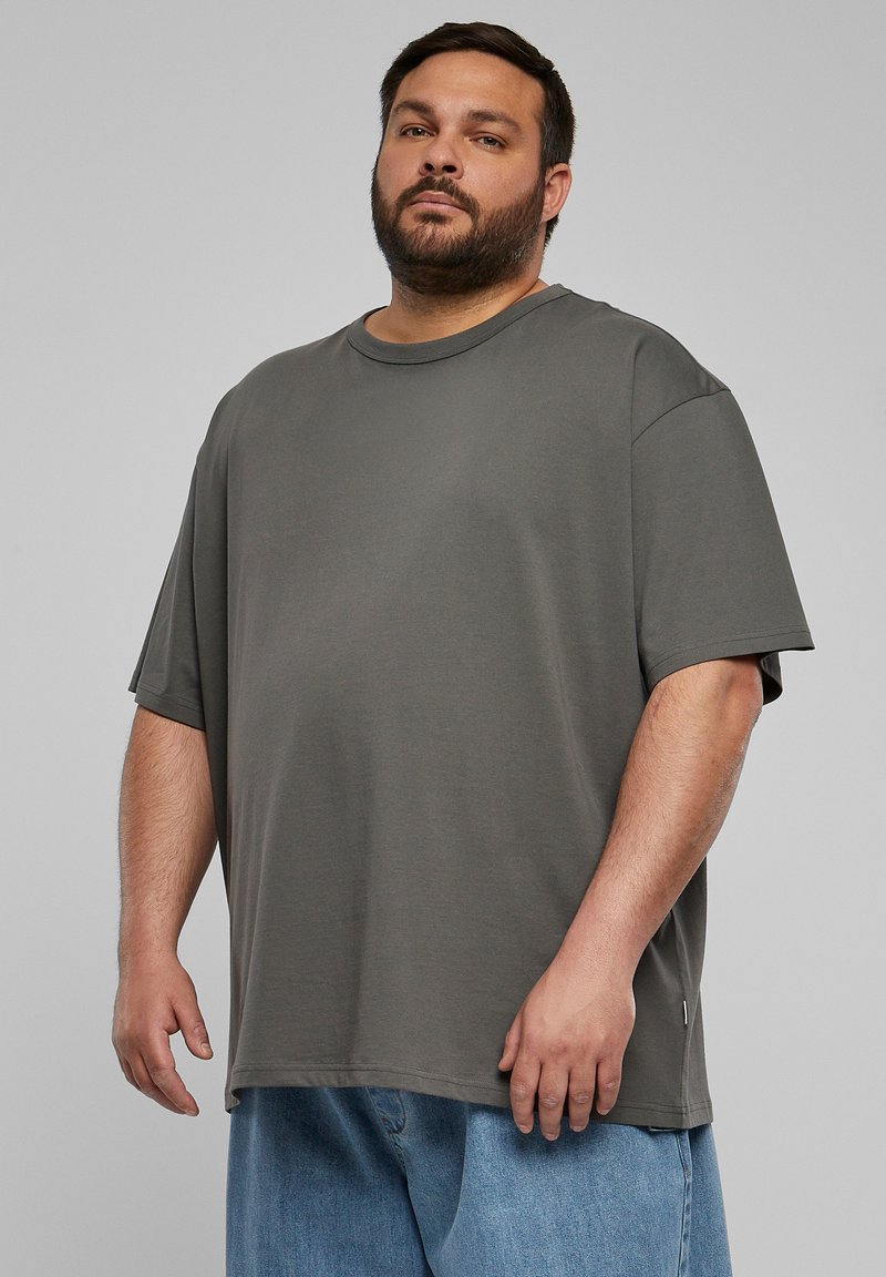 Übergroßes graues T-Shirt aus Jersey-Material mit Rundhalsausschnitt, kurzen Ärmeln und geradem Saum, kombiniert mit hellblauen Jeansshorts.