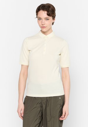 Světle béžové polo tričko s krátkým rukávem, tříkrát knoflíkovou légou a malým logem na hrudi. Hladká, elastická látka.