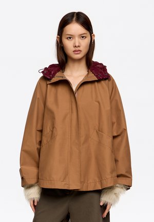 Chaqueta marrón con capucha acolchada burdeos, dos bolsillos frontales y acentos de piel en los puños; diseño de corte holgado.