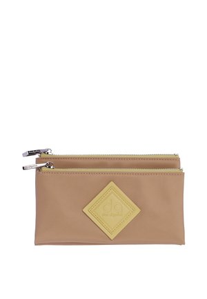 Dos bolsas beige con cremallera, una colocada detrás de la otra, con un parche de logo amarillo en forma de diamante con las iniciales "da" en la bolsa delantera.