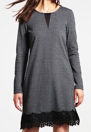 Robe grise à motifs avec des manches longues, un col en V et une bordure en dentelle noire à l'ourlet. Fabriquée en tissu texturé.