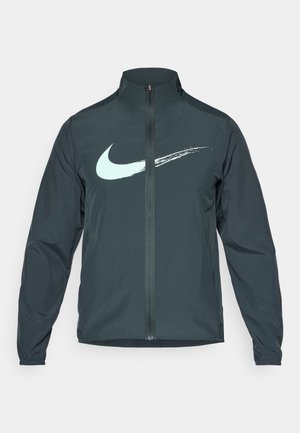 Nike windbreaker jas in donkergroen, met een lichtblauwe Swoosh-logo. Volledige ritssluiting aan de voorkant, hoge kraag en elastische manchetten. Glad, lichtgewicht materiaal.