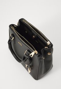 Schwarze Lederhandtasche mit goldenen Beschlägen, zwei Reißverschlussfächern, strukturiertem Design und kurzen Griffen. Das Innere verfügt über eine Taschenanordnung.