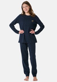 Navy pyjama set met rode en witte stippen, voorzien van lange mouwen en elastische manchetten, aangevuld met een klein gouden hartaccent.