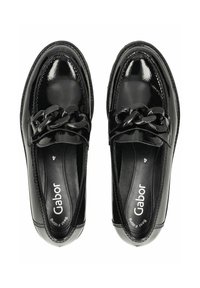 Zapatos de charol negro con un acento trenzado en la parte delantera, con forma redondeada, textura suave y plantillas acolchadas.